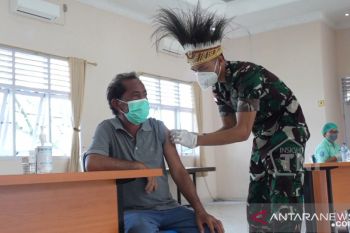 Prajurit TNI gunakan hiasan kepala khas Papua gelar vaksinasi warga