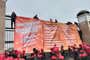 Buruh bentangkan spanduk berisi tuntutan di pagar gedung DPR RI