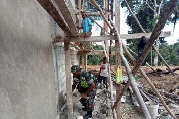 Babinsa bersama warga bergotong royong plester tembok kantor klasis