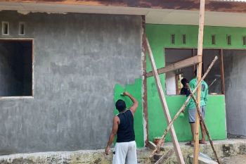 Anggota Satgas TMMD bersama warga mengecat rumah Kampung Sorido