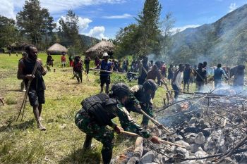 Prajurit TNI Satgas Yonif 511/DY mendukung prosesi "bakar batu" sambut Natal