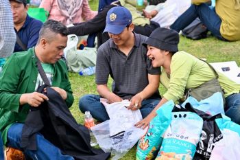 Warga membuka kemas paket sembako di Bazar Rakyat Monas