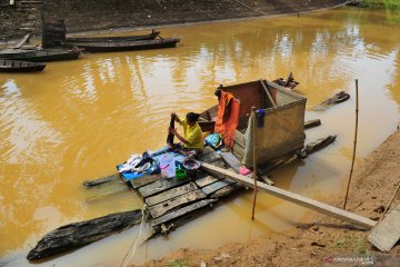 Warga mencuci pakaian di sungai yang keruh