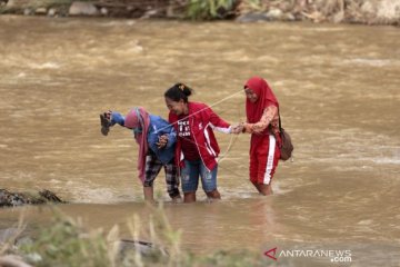 Foto - Warga Bone Bolango lintasi sungai deras setelah jembatan hanyut