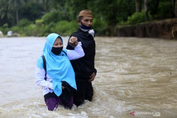 Siswa dan guru menyeberangi sungai untuk belajar mengajar