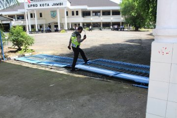 Anggota polisi melintasi pintu pagar DPRD Kota Jambi yang roboh