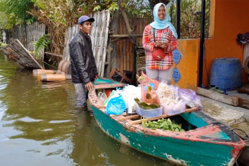 Jajakan sayur dengan perahu di tengah banjir