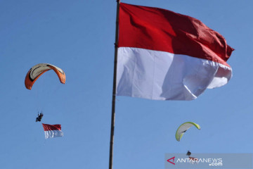 Pengibaran bendera Merah Putih di langit Bali dengan paralayang