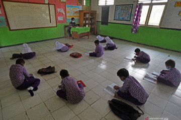 Siswa belajar di lantai akibat bangku sekolah lapuk