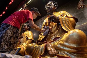 Membersihkan patung di Klenteng Tay Kak Sie