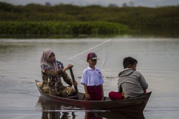 Guru dan murid naik perahu ke sekolah