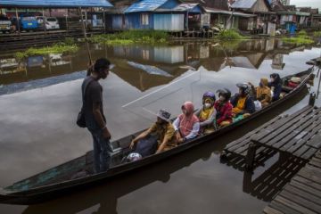 Guru dan murid naik perahu ke sekolah