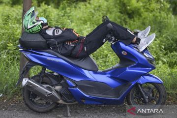 Pemudik bersepeda motor istirahat tidur di tepi Jalan Pantura