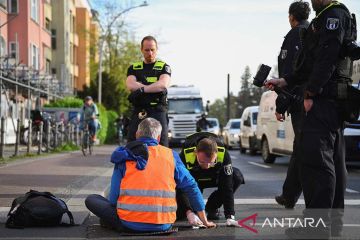 Pengunjuk rasa mengelem dirinya di jalan kota Berlin