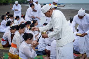 Pemuka agama Hindu memercikkan air suci saat upacara Melasti di Pantai Tanjung Pasir