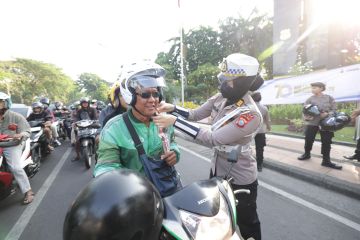 Polwan Polda Jatim "gatur lalin" sambil berbagi helm dan cokelat