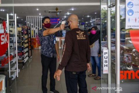 Petugas lakukan pengukuran suhu tubuh pengunjung pusat perbelanjaan di Palu