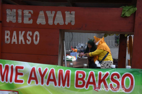 Sambil berdagang, seorang ibu dampingi anaknya belajar