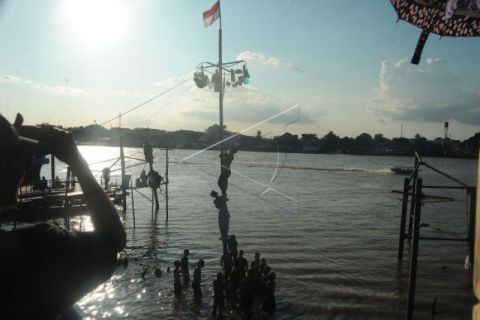 Lomba Panjat Pinang di Bantaran Sungai Musi