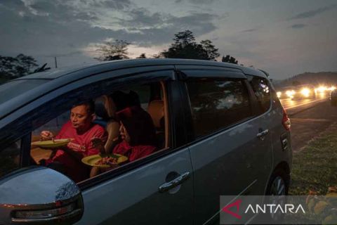 Pemudik berbuka puasa dengan bekal di sekitar rest area