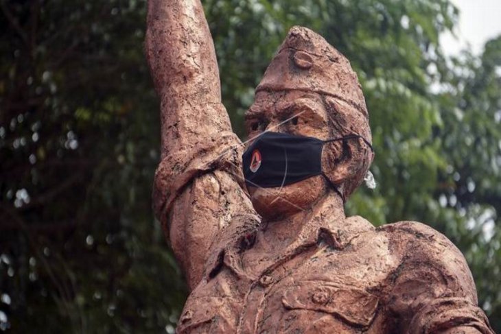 Memasang masker di patung Monumen Djoeang 45