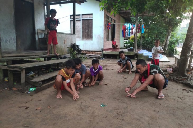 Anggota TMMD ikut bermain kelereng bersama anak-anak