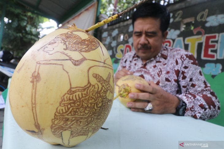 Perajin  gambar wayang pada kelapa