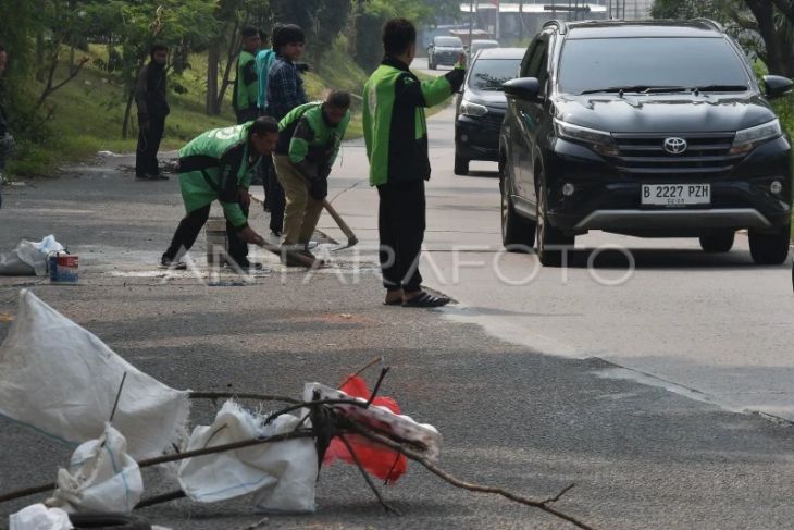 Driver Ojol menambal jalan berlubang di Bekasi