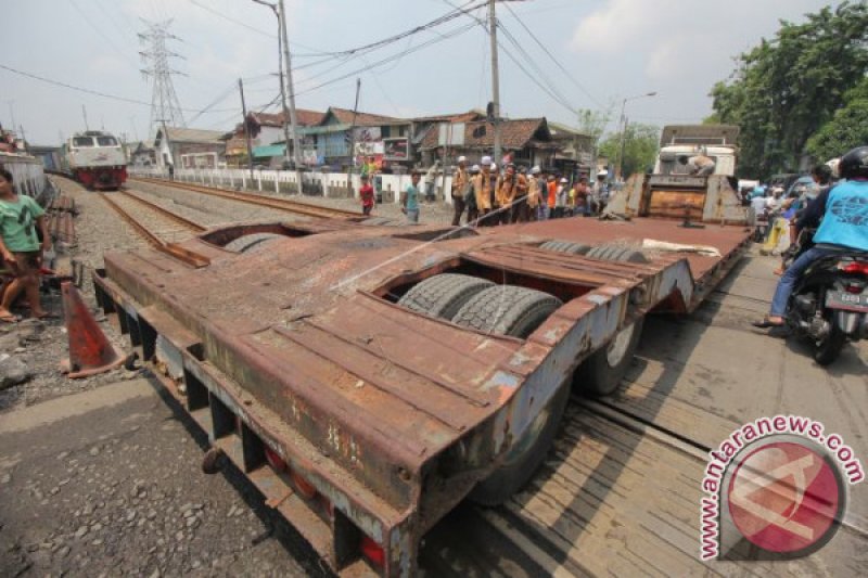 TRUK TRAILER TERSANGKUT REL