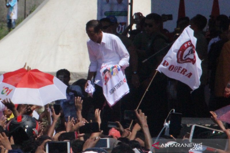 Jokowi sedang membagi kaos kepada lautan manusia di Lapangan Sitarda Kupang