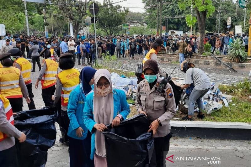 Mahasiswa bersama polisi bersih-bersih sampah usai demo