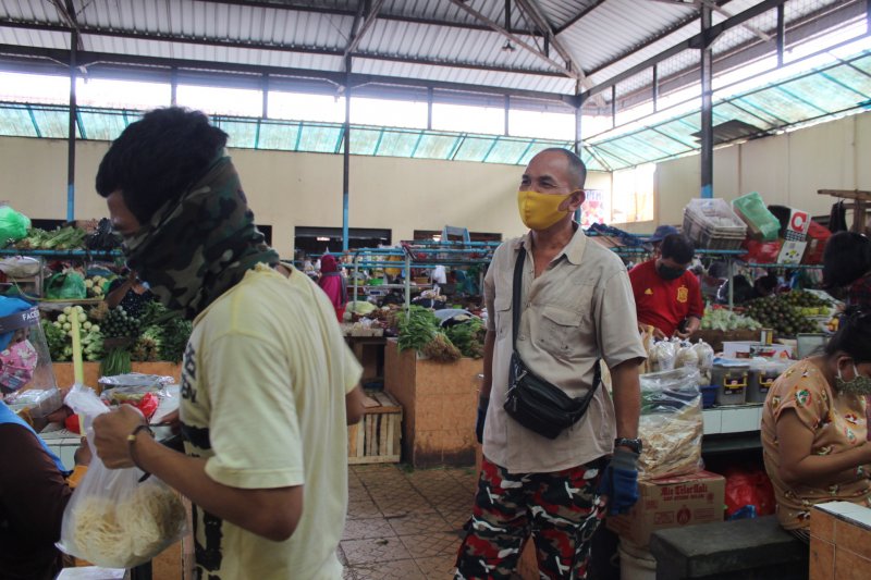 Seorang petugas pasar tengah mengingatkan masyarakat menggunakan masker