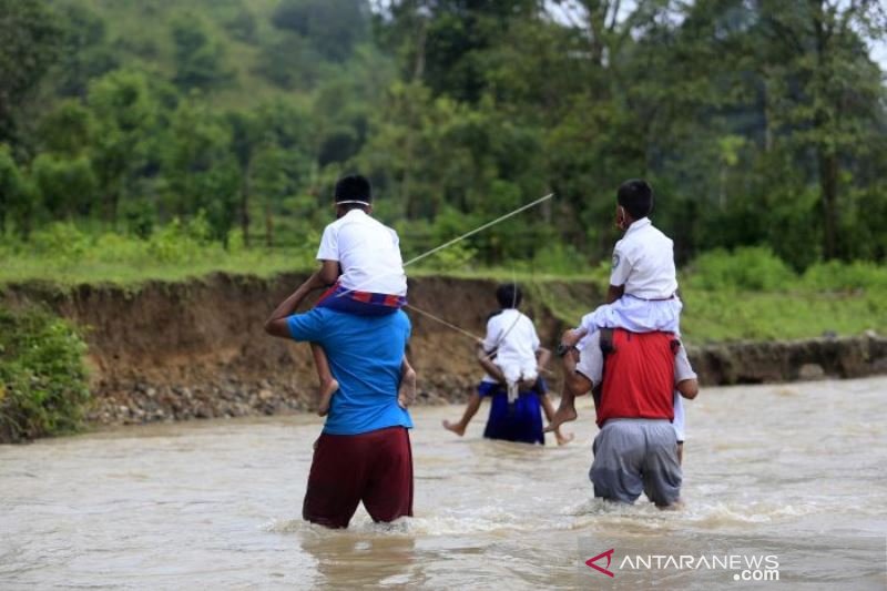 SISWA DAN GURU MENYEBERANGI SUNGAI UNTUK BELAJAR MENGAJAR