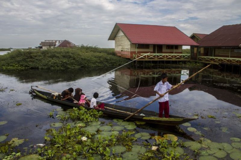 Guru dan murid naik perahu ke sekolah