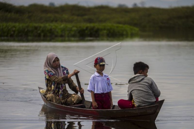 Guru dan murid naik perahu ke sekolah